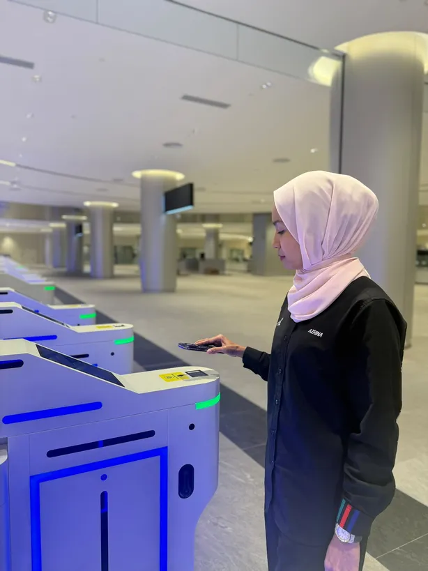 An MRT Corp staff member demonstrating the QR scan at an autogate in the immigration hall
