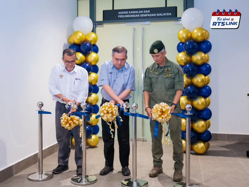 Three officials, including the Minister of Transport, cutting ribbons at the AKPS office opening ceremony, flanked by blue-and-gold balloon columns