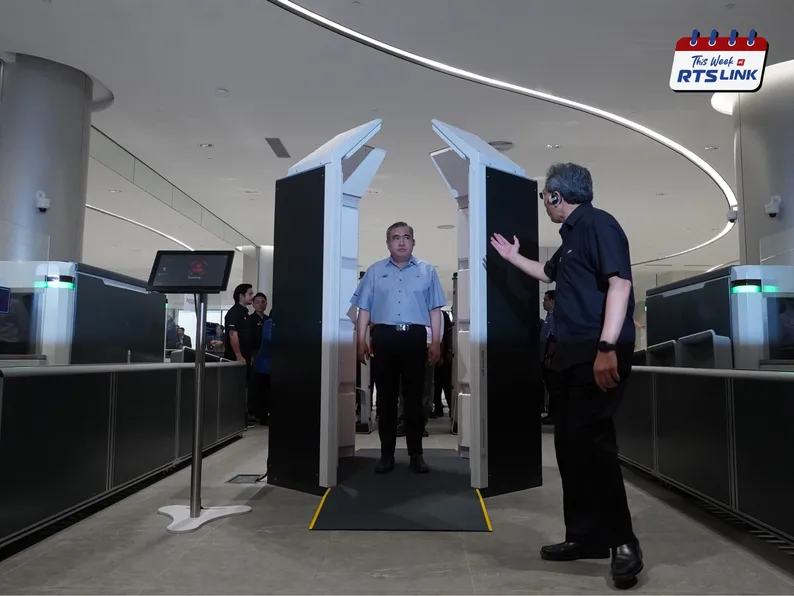 YB Loke Siew Fook standing in an OPS Walk 2000 body scanner at the ICQ Complex security screening hall, with an official gesturing beside the machine and a “Scanning…” display alongside