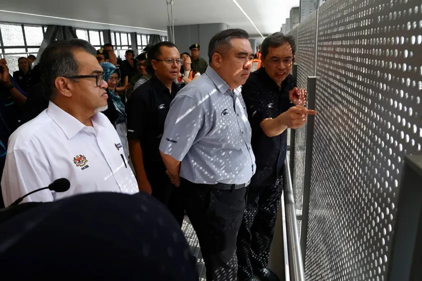 Officials inspecting the perforated screen facade at an RTS Link station during a site visit