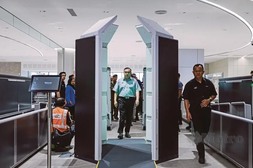 Transport Minister Anthony Loke walking through a body scanner during a security demonstration