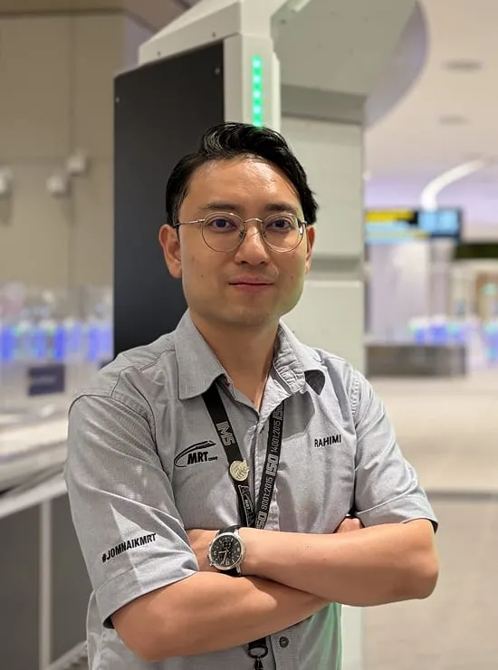 A man wearing a lanyard standing between two security screening gates in the departure hall